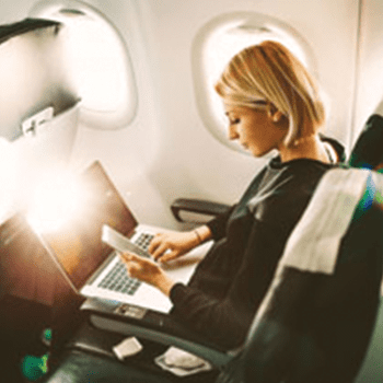 A person sitting in an airplane seat looking at their phone 